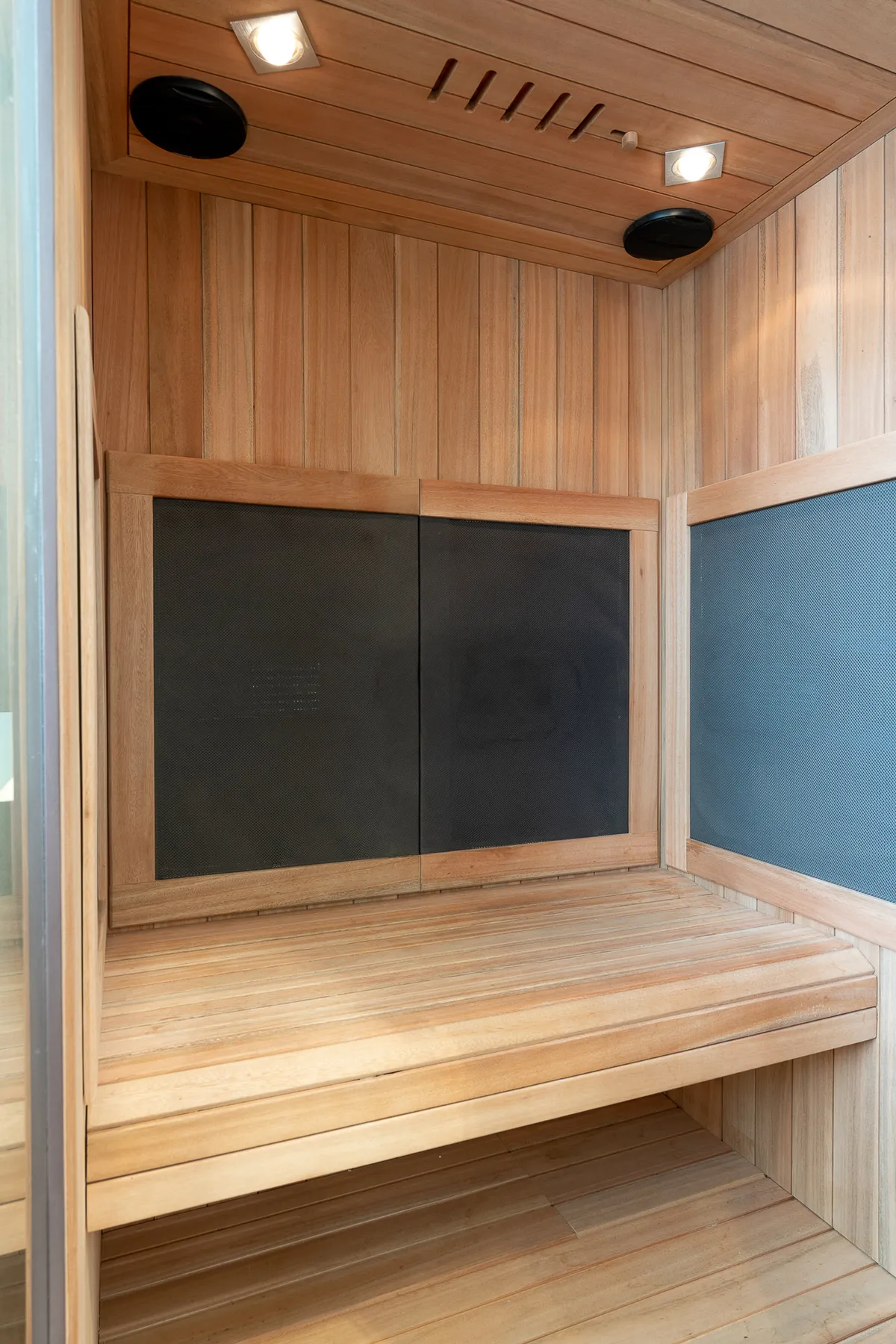 A serene interior wellness space featuring wooden benches and paneling, illuminated by soft lighting. The environment invites relaxation and moments of personal rejuvenation, ideal for unwinding after a busy day.