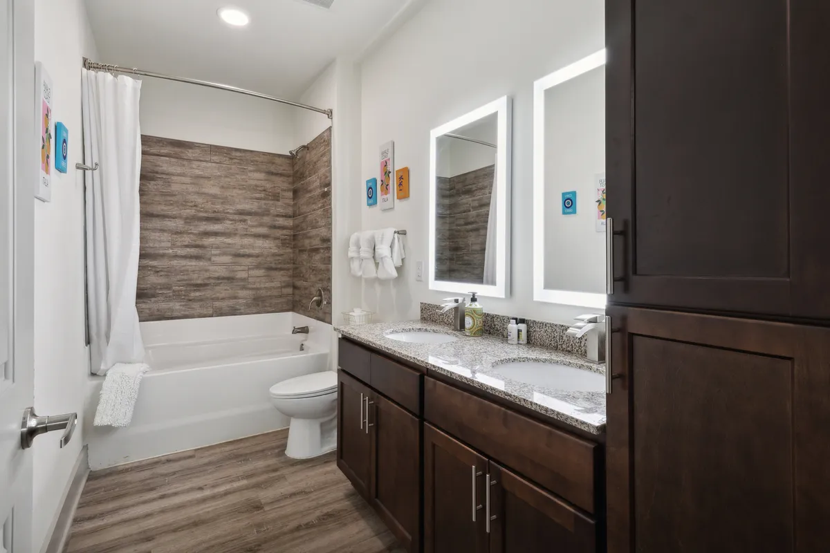 A spacious, spa-inspired bathroom with double sinks, wide mirrors, and a modern bathtub. The neutral color palette and clean lines create an inviting and tranquil atmosphere, reminiscent of a boutique spa experience.