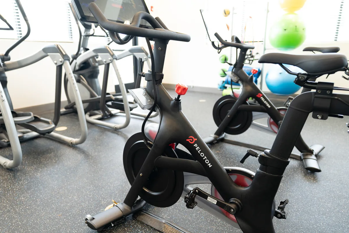 A vibrant in-building fitness area, complete with a Peloton bike, elliptical machines, and a selection of colorful exercise balls. The scene suggests opportunities for personal fitness journeys and energetic group workouts.